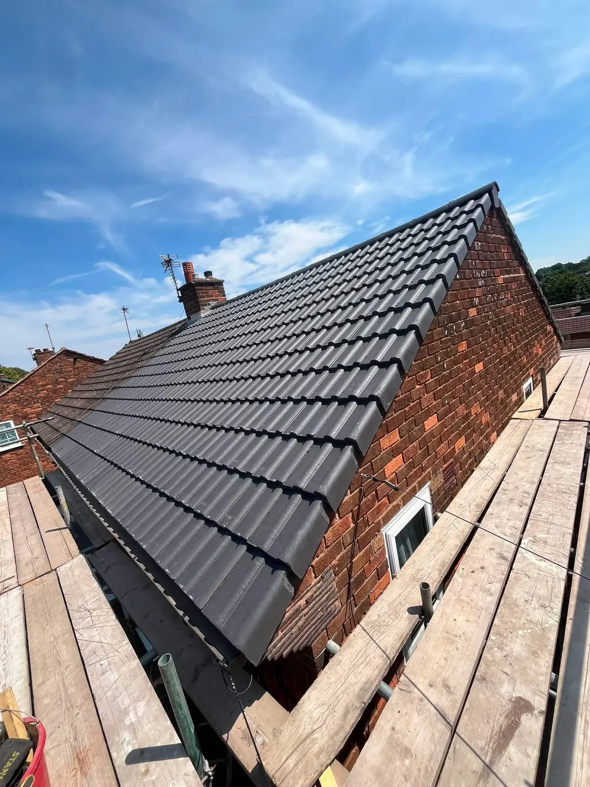 Grey tiled roof against brickwork