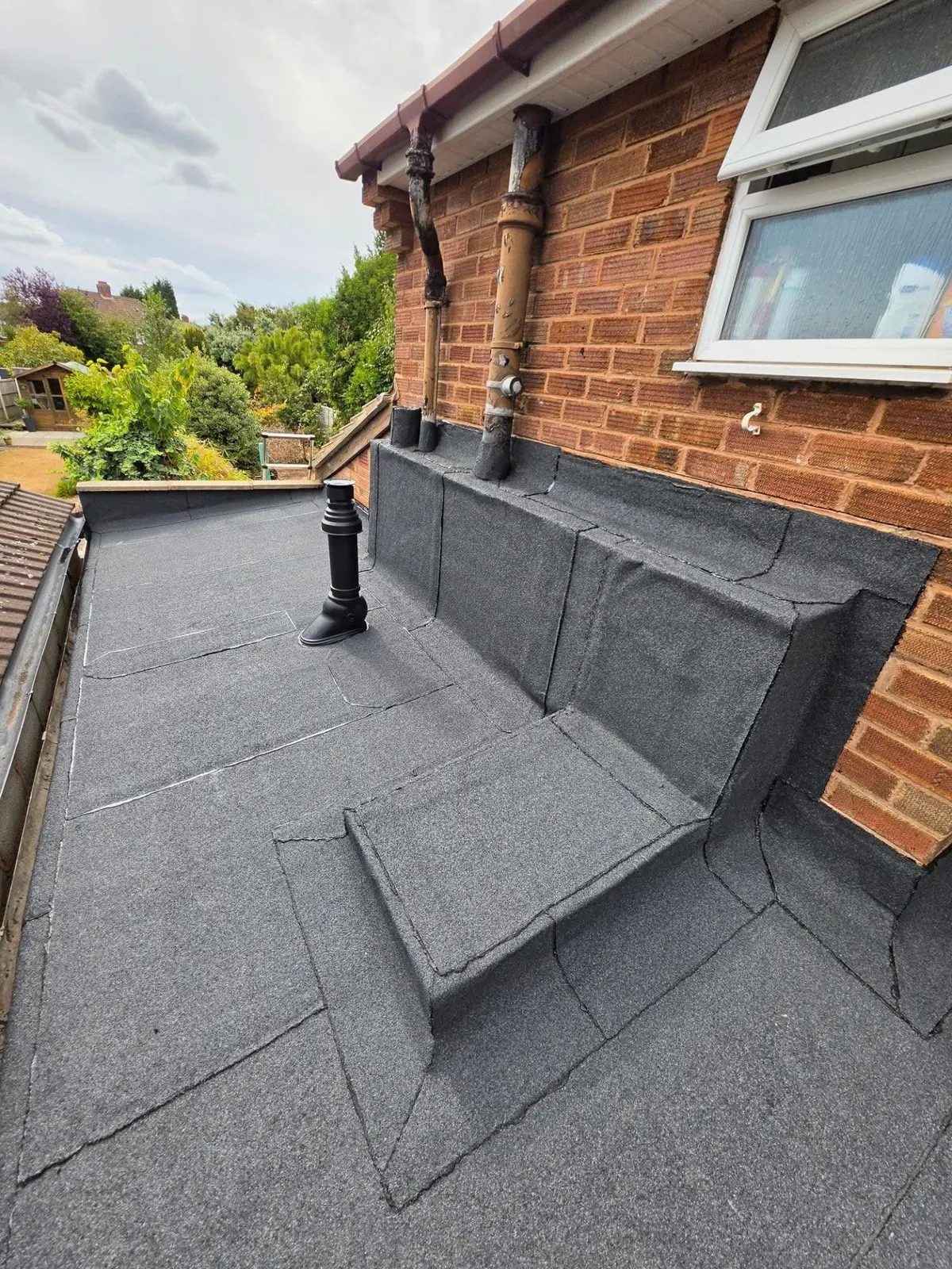 Felt flat roof against a house wall